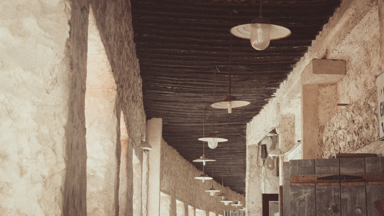 a woman walking down a long hallway between two buildings