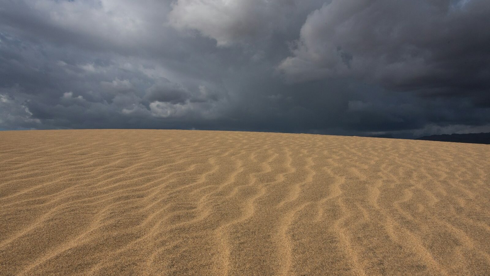 a large sand dune under a cloudy sky